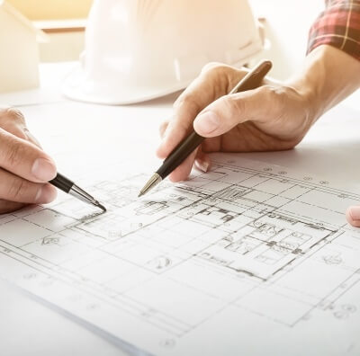 Two people are holding pens and going through construction drawings