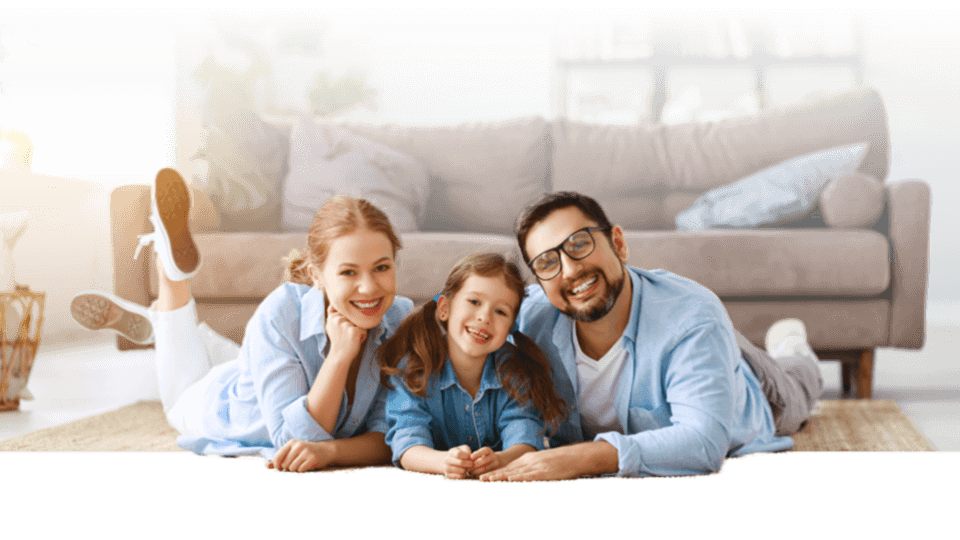 Father mother and daughter in the living room sitting on the floor and smiling at the camera