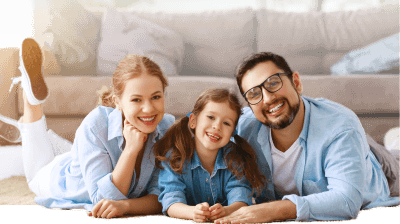 Father mother and daughter in the living room sitting on the floor and smiling at the camera